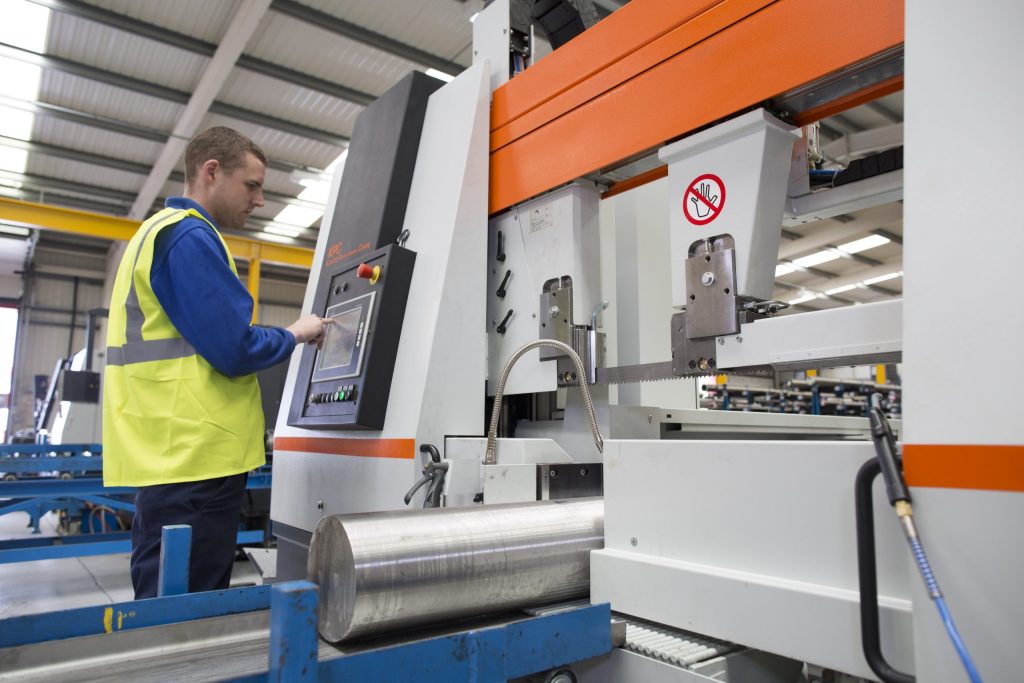 Technician operating a CNC bar saw in the Langley Alloys workshop